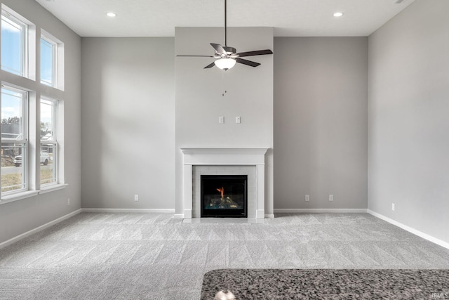 unfurnished living room with carpet floors, a fireplace, baseboards, and recessed lighting