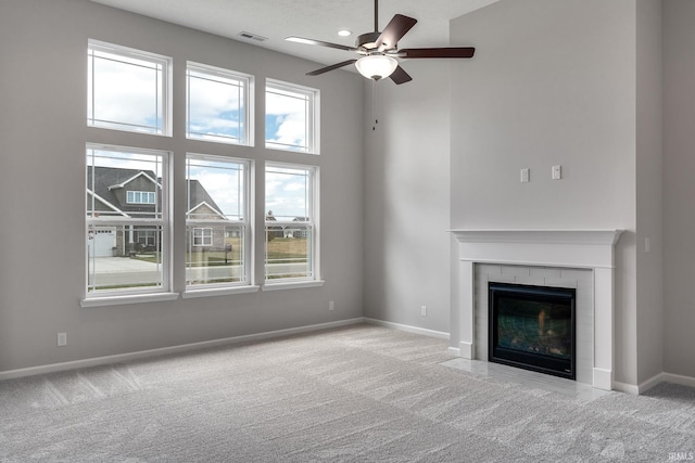 unfurnished living room with carpet floors, a tile fireplace, and baseboards