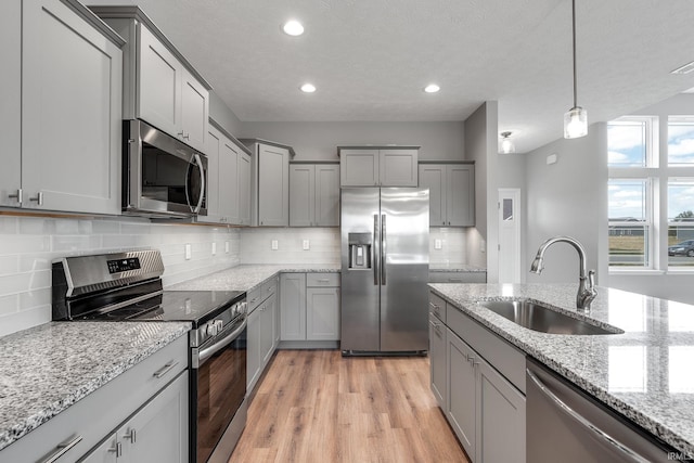 kitchen featuring appliances with stainless steel finishes, gray cabinets, and a sink