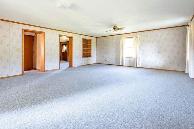 empty room featuring wallpapered walls, baseboards, a ceiling fan, carpet, and crown molding