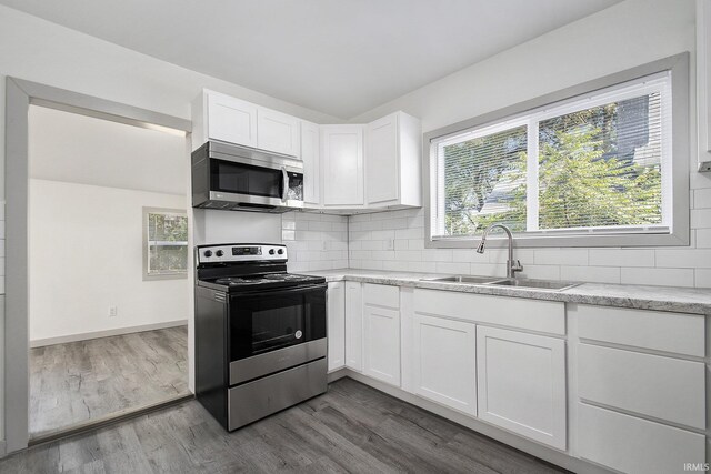 kitchen featuring sink, wood-type flooring, tasteful backsplash, white cabinetry, and stainless steel appliances