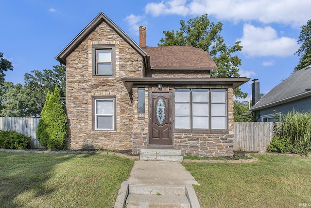 traditional-style home with a front lawn, fence, roof with shingles, a chimney, and stone siding