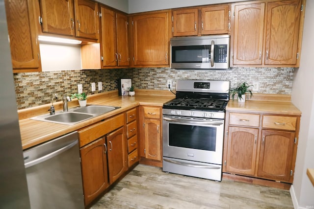 kitchen with light countertops, appliances with stainless steel finishes, a sink, and light wood-style flooring