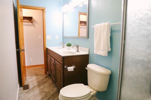 full bathroom with double vanity, wood finished floors, a sink, and toilet