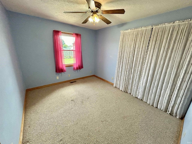 carpeted empty room featuring visible vents, ceiling fan, a textured ceiling, and baseboards