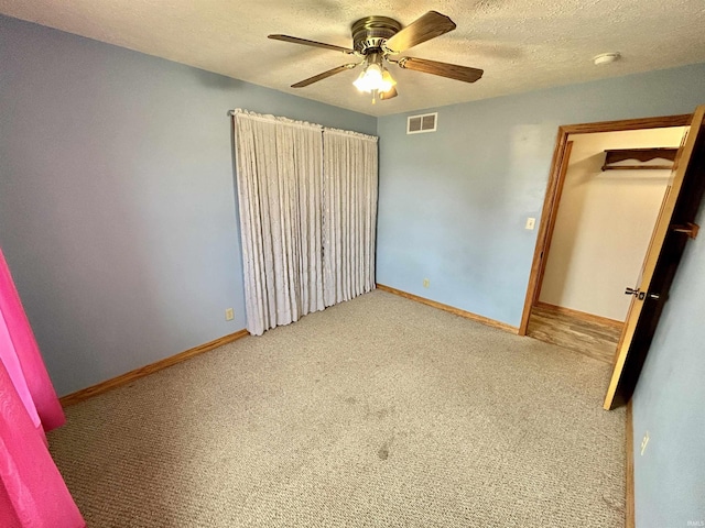 unfurnished bedroom featuring baseboards, a textured ceiling, visible vents, and carpet flooring