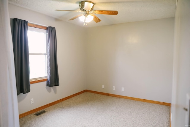 carpeted empty room with baseboards, a textured ceiling, visible vents, and a ceiling fan