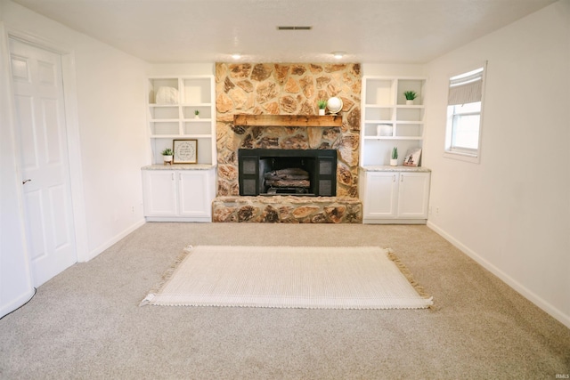 unfurnished living room featuring carpet floors, built in shelves, a fireplace, and visible vents