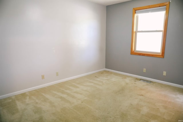 carpeted spare room with visible vents and baseboards