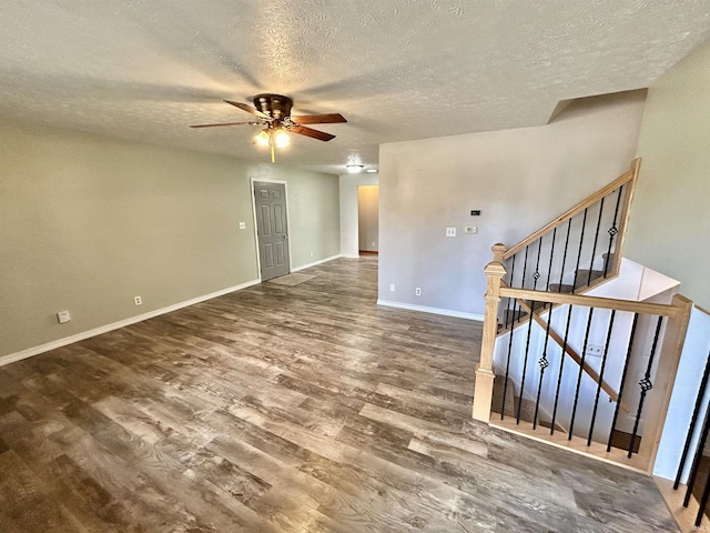 interior space with stairway, a ceiling fan, a textured ceiling, wood finished floors, and baseboards