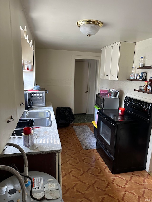 kitchen with light parquet flooring, white cabinets, sink, and black range with electric cooktop