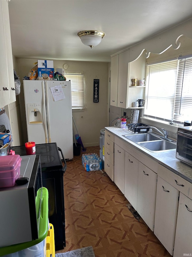 kitchen with white refrigerator with ice dispenser, sink, and white cabinetry