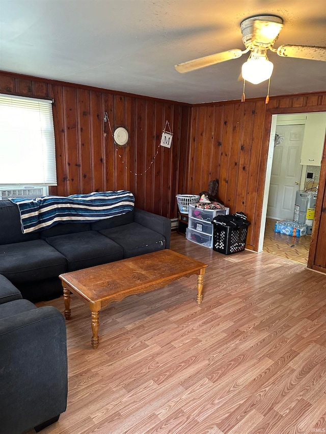 living room with light hardwood / wood-style flooring, wood walls, and ceiling fan