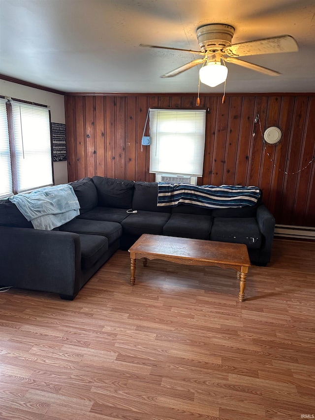 living room with hardwood / wood-style flooring, ceiling fan, and wooden walls