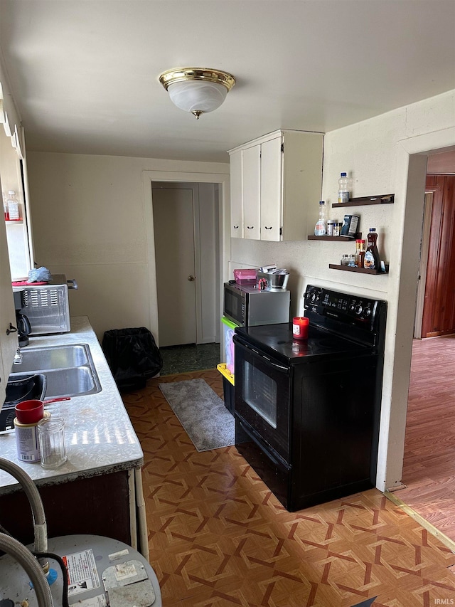 kitchen featuring white cabinets, black electric range oven, and sink