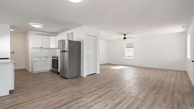 kitchen with black electric range oven, stainless steel fridge, ceiling fan, white cabinetry, and light hardwood / wood-style flooring