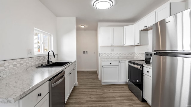 kitchen featuring tasteful backsplash, sink, hardwood / wood-style floors, stainless steel appliances, and white cabinets