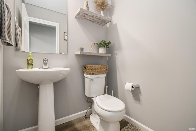 half bathroom with toilet, baseboards, and wood finished floors