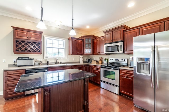 kitchen with appliances with stainless steel finishes, dark hardwood / wood-style floors, sink, crown molding, and a center island