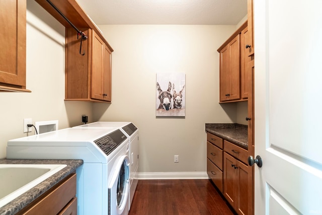 clothes washing area with washing machine and clothes dryer, dark hardwood / wood-style flooring, and cabinets