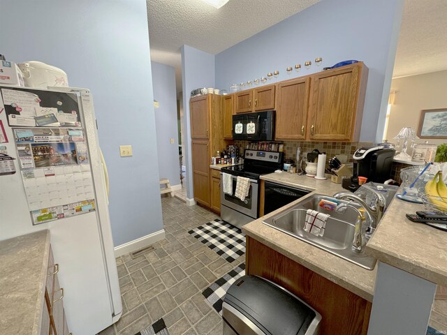 kitchen featuring a textured ceiling, backsplash, black appliances, sink, and a breakfast bar area