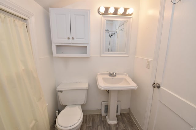 bathroom with curtained shower, toilet, and wood-type flooring