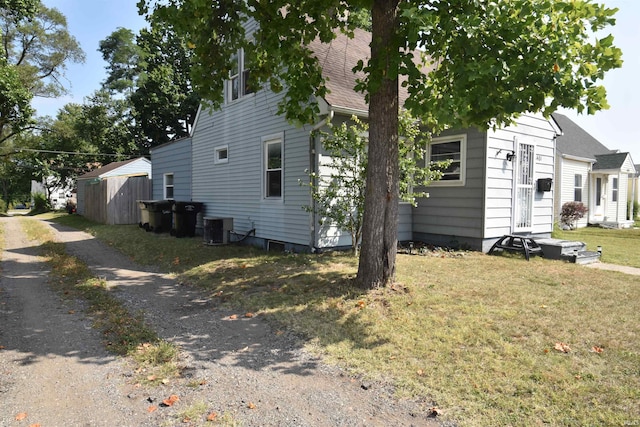 view of side of property featuring central air condition unit, a storage shed, and a lawn