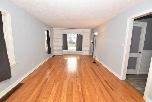 unfurnished room featuring a textured ceiling and light hardwood / wood-style floors