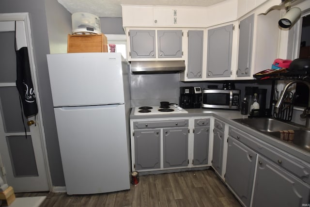 kitchen featuring gray cabinetry, white appliances, dark wood-type flooring, and wall chimney exhaust hood