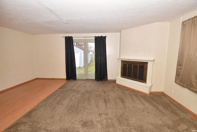 unfurnished living room with a large fireplace and carpet flooring