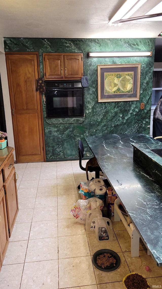 kitchen with dark stone countertops, light tile patterned floors, and oven