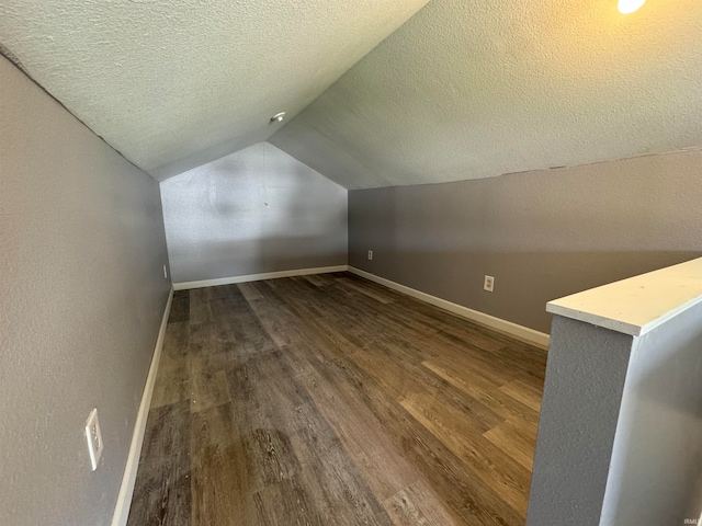 additional living space with vaulted ceiling, wood-type flooring, and a textured ceiling