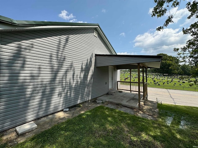 view of side of property with a patio area and a lawn