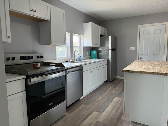 kitchen with light hardwood / wood-style flooring, white cabinets, appliances with stainless steel finishes, butcher block counters, and sink