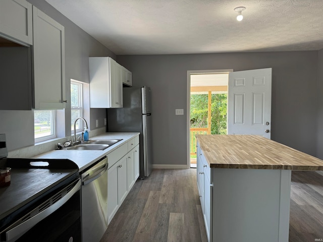 kitchen featuring appliances with stainless steel finishes, a center island, sink, wood-type flooring, and wood counters