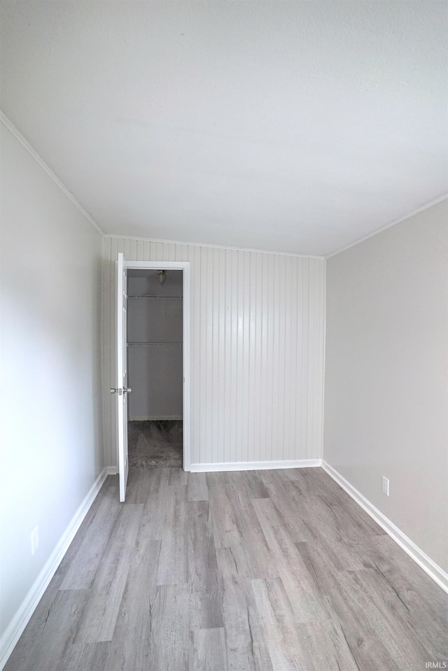 unfurnished bedroom with hardwood / wood-style flooring, a closet, crown molding, and a walk in closet