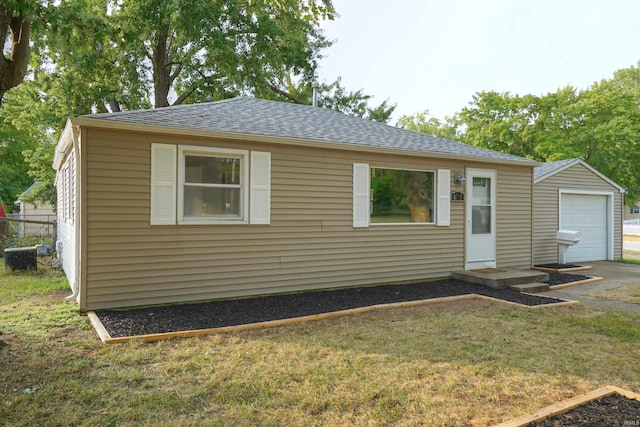 view of front of house with an outbuilding, roof with shingles, a front yard, and a detached garage