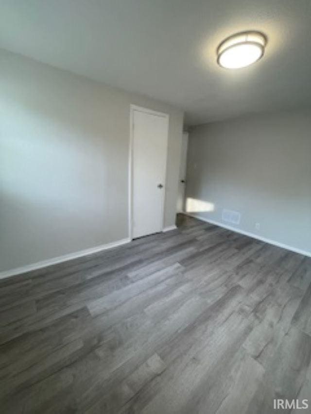 unfurnished room with dark hardwood / wood-style flooring