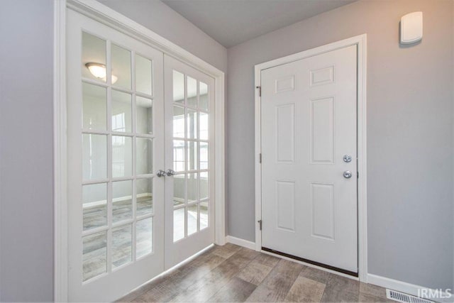 doorway with hardwood / wood-style floors, plenty of natural light, and french doors