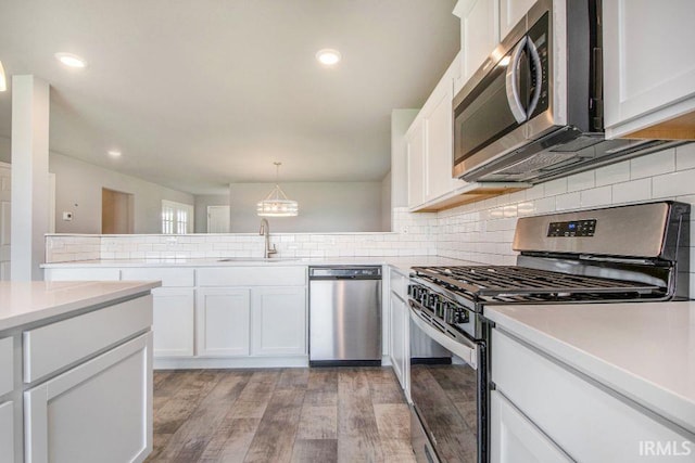 kitchen featuring light wood-type flooring, tasteful backsplash, white cabinetry, appliances with stainless steel finishes, and kitchen peninsula