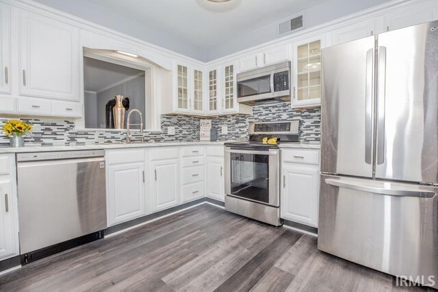 kitchen with decorative backsplash, dark wood-type flooring, white cabinetry, appliances with stainless steel finishes, and light stone countertops