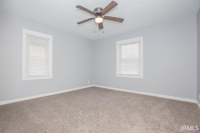 carpeted empty room with ceiling fan and baseboards