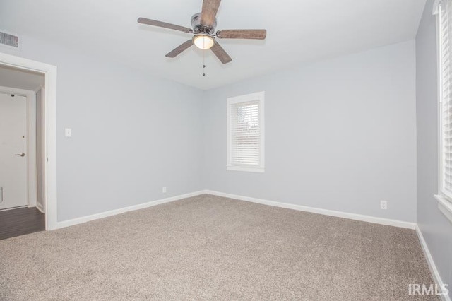 carpeted empty room with ceiling fan, visible vents, and baseboards