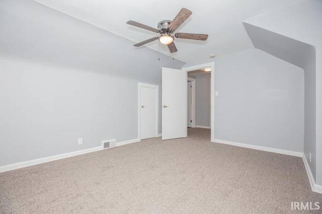 additional living space with carpet, visible vents, a ceiling fan, vaulted ceiling, and baseboards