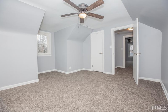 additional living space featuring light colored carpet, vaulted ceiling, baseboards, and ceiling fan