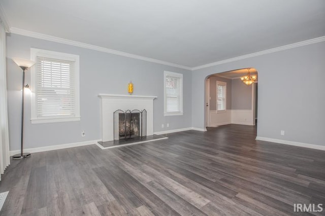 unfurnished living room featuring baseboards, arched walkways, a fireplace with raised hearth, ornamental molding, and dark wood-style flooring