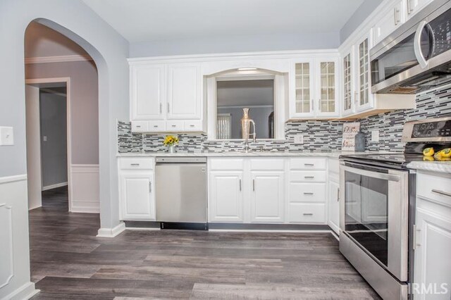 kitchen with stainless steel appliances, white cabinetry, dark hardwood / wood-style floors, tasteful backsplash, and sink