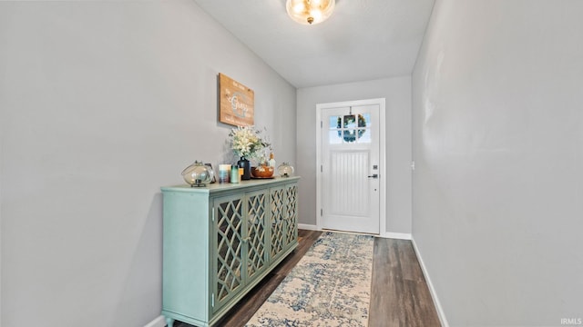 doorway featuring baseboards and dark wood finished floors