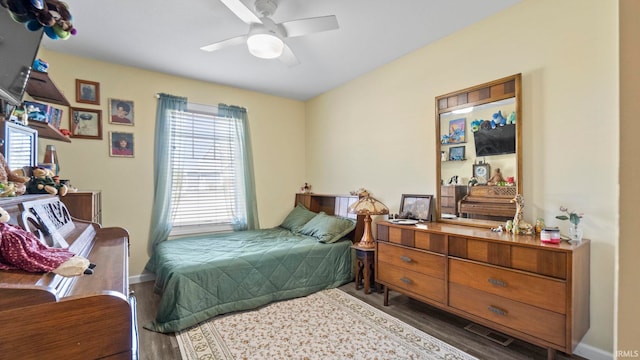 bedroom featuring a ceiling fan, multiple windows, baseboards, and wood finished floors