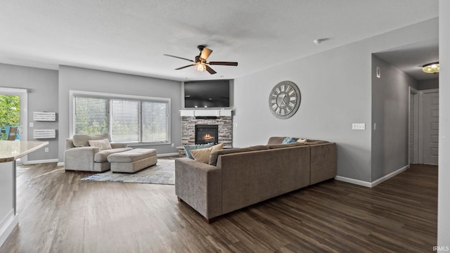 living room featuring dark wood-style floors, baseboards, and a stone fireplace